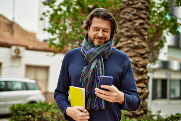 Fototapeta premium Middle age handsome man using smartphone outdoors at the park