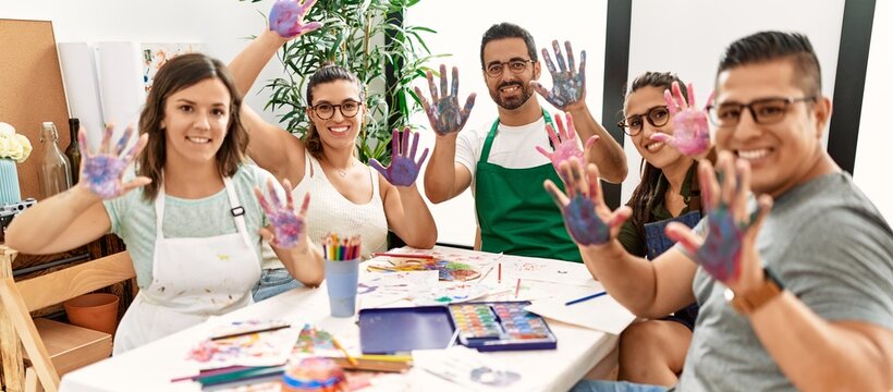 Group of draw students sitting on the table showing painted palm hands at art studio.