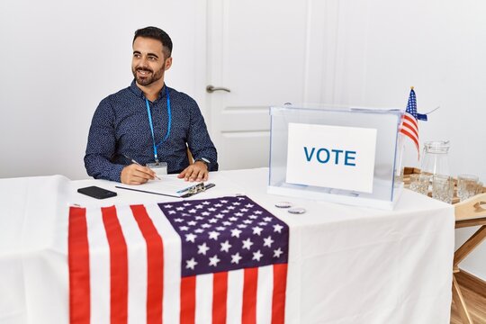 Young hispanic man smiling confident writing on clipboard working at electoral college