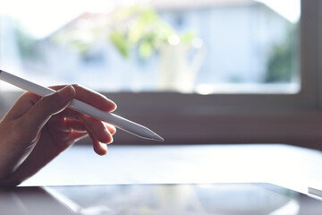 Woman using stylus pen on digital tablet and working from home office, close up © tippapatt