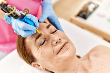 Middle age caucasian woman having anti-aging face treatment at beauty center