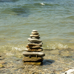 a large tower of flat stones sand pebbles on the background of the sea.