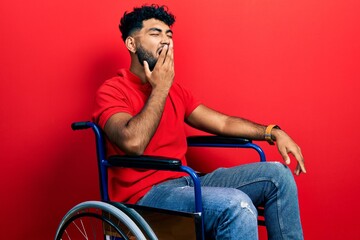 Arab man with beard sitting on wheelchair bored yawning tired covering mouth with hand. restless and sleepiness.