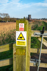 Sheep Grazing sign attached to a wooden gate on the Ward Way public footpath instructing dog owners to keep their dog on a lead.