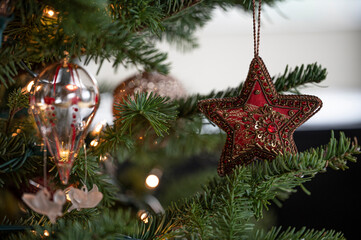 Red decorative star ornament hanging on a Christmas tree