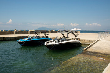 Fototapeta na wymiar two high-speed boats moored to the pier against the background of the sea and a concrete breakwater
