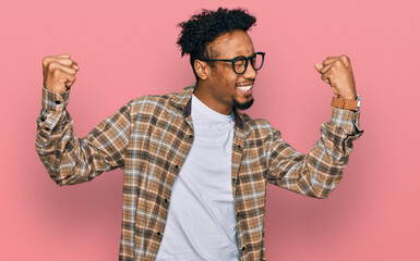Fototapeta premium Young african american man with beard wearing casual clothes and glasses very happy and excited doing winner gesture with arms raised, smiling and screaming for success. celebration concept.