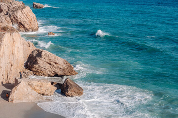 Aerial top view of sea waves hitting rocks on the beach with turquoise sea water. 