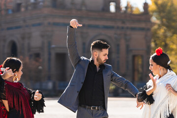 Man dancing flamenco next to two women in a square