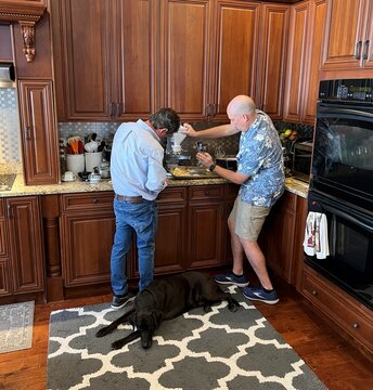 men cooking in the kitchen with their dog
