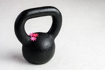 Obraz na płótnie Canvas Kettlebell spring fitness, black kettlebell on a white background with silver sparkles and red, pink, and white flowers 