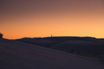 Silhouette of hiker during sunset on sand dunes
