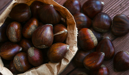 Chestnuts in a paper bag on a wooden background
