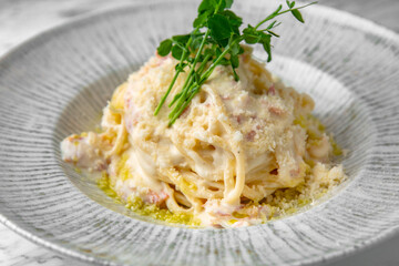 Carbonara paste in a festive plate on a marble background. Restaurant banquet menu.