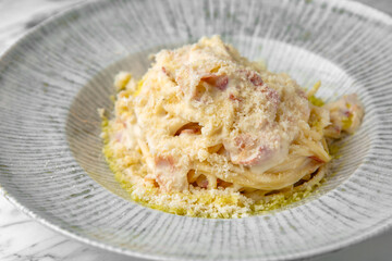 Carbonara paste in a festive plate on a marble background. Restaurant banquet menu.