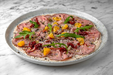 Pork carpaccio with truffle in a festive plate on a marble background. Restaurant banquet menu.