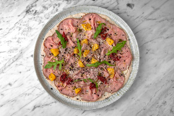 Pork carpaccio with truffle in a festive plate on a marble background. Restaurant banquet menu.