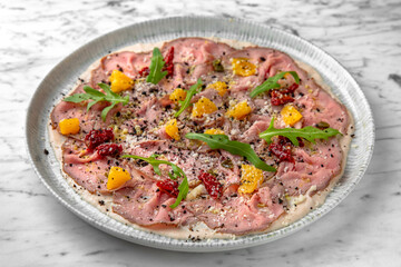 Pork carpaccio with truffle in a festive plate on a marble background. Restaurant banquet menu.