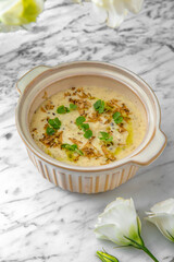 Creamy soup made from chickpeas, cheese and olive oil. Healthy Hearty  Nutritious Lunch in a festive plate on a marble background. Restaurant banquet menu.