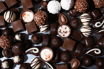 Many different delicious chocolate candies on metal surface, top view