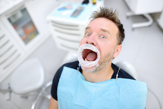Frightened patient in the chair on dental clinic. Orthodontist and prosthetics appointment. Fear of dentists concept.