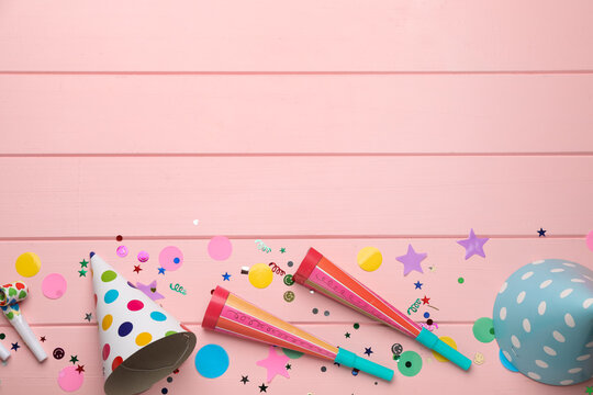 Flat lay composition with party items on pink wooden table, space for text