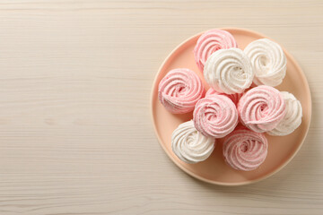 Plate with delicious marshmallows on wooden table, top view. Space for text
