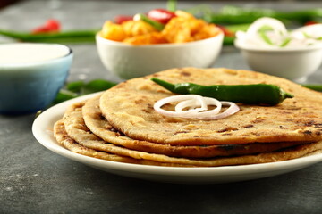 Indian vegetarian meal- healthy vegan diet - aloo paratha served with spicy potato curry and raita,.
