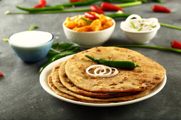 Indian vegetarian meal- homemade whole wheat aloo paratha served with potato curry and fresh raita