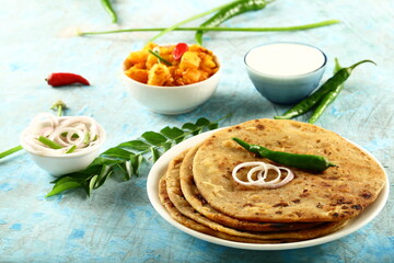 Fototapeta na wymiar Homemade delicious Indian vegan diet meal- aloo paratha with potato curry and fresh raita.