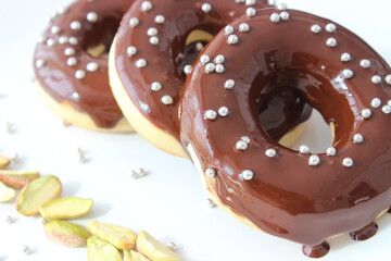 Chocolate donut decorated with gray dragee. peanuts on a white plate