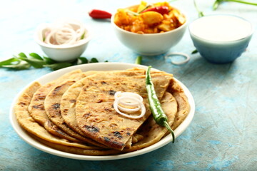 Indian vegetarian meal- homemade whole wheat aloo paratha served with potato curry and fresh raita