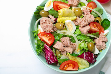 Bowl of delicious salad with canned tuna and vegetables on white table, top view