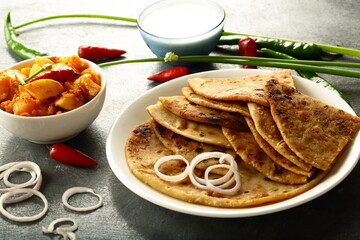 Indian vegan wholesome meal- homemade traditional Indian vegetarian food- aloo paratha served with fresh raita and potato curry masala.