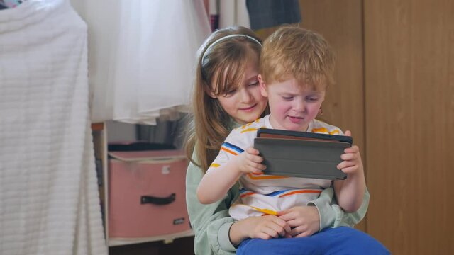 Girl encouraging the boy children play on tablet