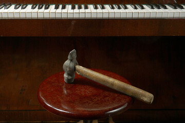A hammer on a chair against the background of piano keys. An example of a stupid joke or malicious...