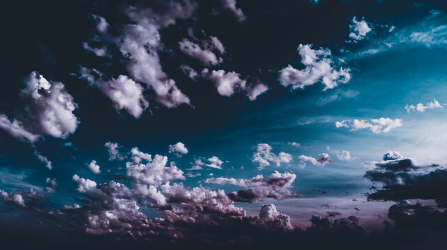 Clouds float across the dark blue evening sky