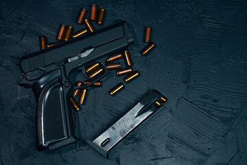Firearms on dark background. Flat lay of gun and cartridge with bullets. Weapons on concrete table. Pistol for defense or attack. Concept of crime ammunition and physical evidence. Copy space.