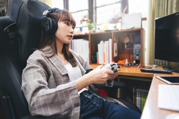 Young adult asian woman hand holding a joy controller wear headset and play game at home © dodotone
