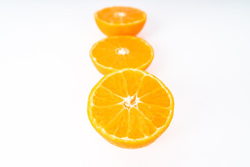 Three half tangerines in a row on a white background