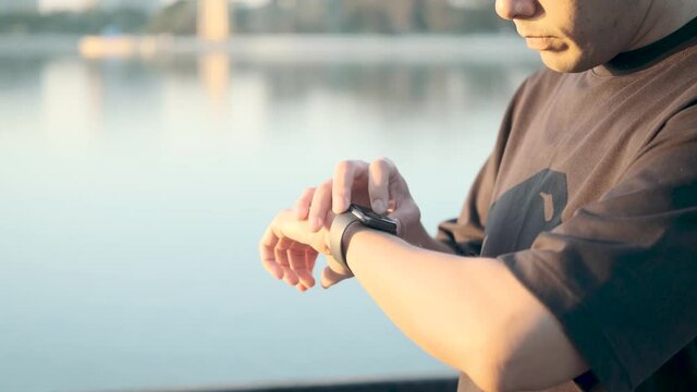 asian men going to exercise by running at the park in the morning at sunrise  Use the smart watch to press start to record and watch the heart rate to stay healthy.