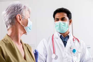 A Young Indian Male Medical Doctor Consults with an Elderly Senior Female Patient about Covid-19...