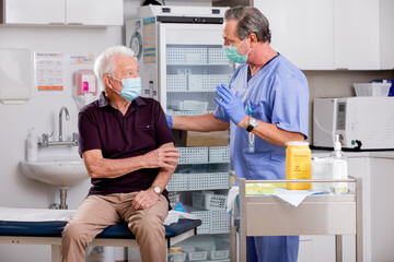 A White Male Medical Nurse Consults with an Elderly Senior Male Patient about Covid-19 Vaccine...