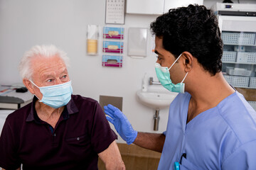A Young Indian Male Medical Nurse Consults with an Elderly Senior Male Patient about Covid-19...