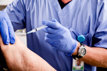 Covid-19 Vaccine Injection Close Up by a Male Nurse with Gloves using a Syringe Needle with Elderly...