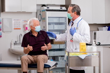 A White Male Medical Doctor Consults with an Elderly Senior Male Patient about Covid-19 Vaccine...
