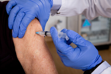 Covid-19 Vaccine Injection Close Up by a Doctor with Gloves using a Syringe Needle with Elderly...
