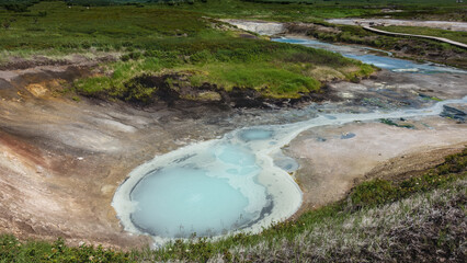 Streams and small lakes with blue opaque water from hot springs are formed in the caldera of an...