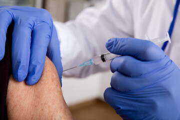 Covid-19 Vaccine Injection Close Up by a Male Doctor with Gloves using a Syringe Needle with...