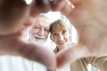 Fototapeta premium portrait senior couple smiling and making a heart shape with their hands